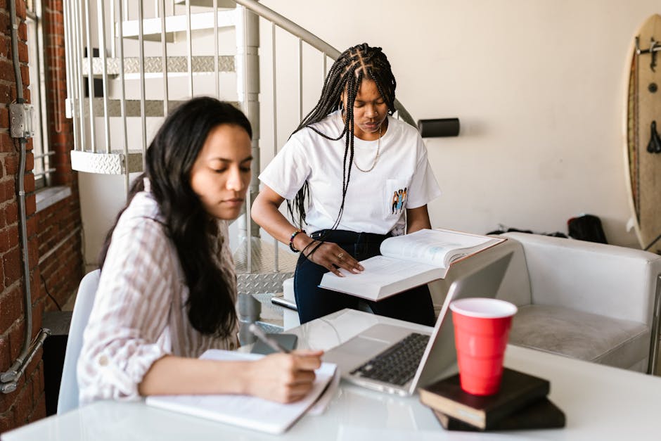College students studying together, using a laptop and books indoors