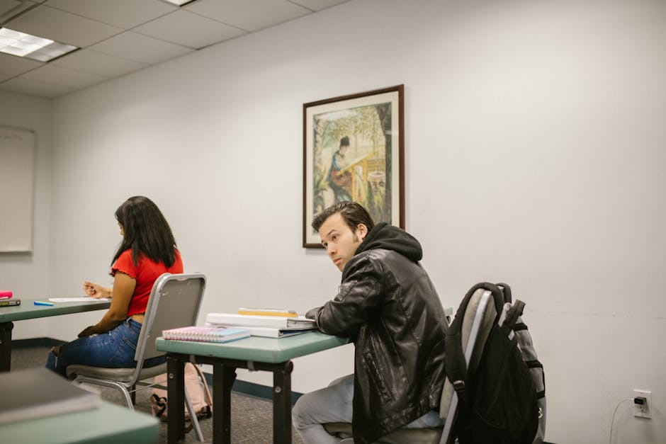 A male and female college students studying in a classroom, focused on their exams